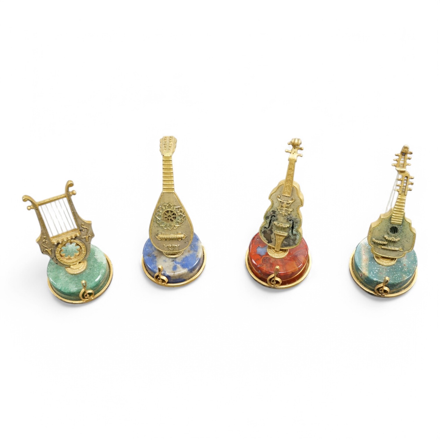 A set of four mid 20th century Italian 800 standard gilt white metal miniature model string instruments, including a lyre and lute, each mounted on a circular hardstone base, including jasper and adventurine quartz, 65mm